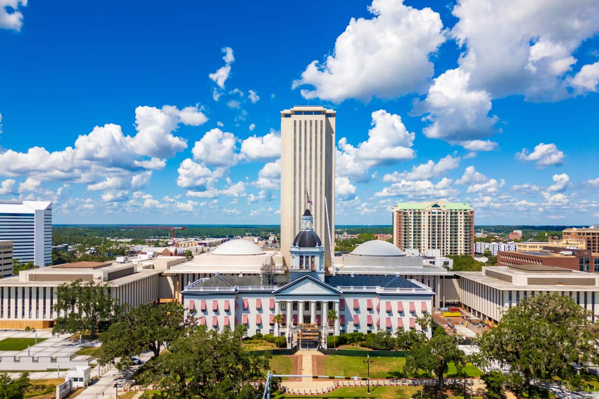 The Florida State Capitol complex in Tallahassee, Florida, with the tall modern capitol tower rising behind the domed Historic Capitol and its striped awnings